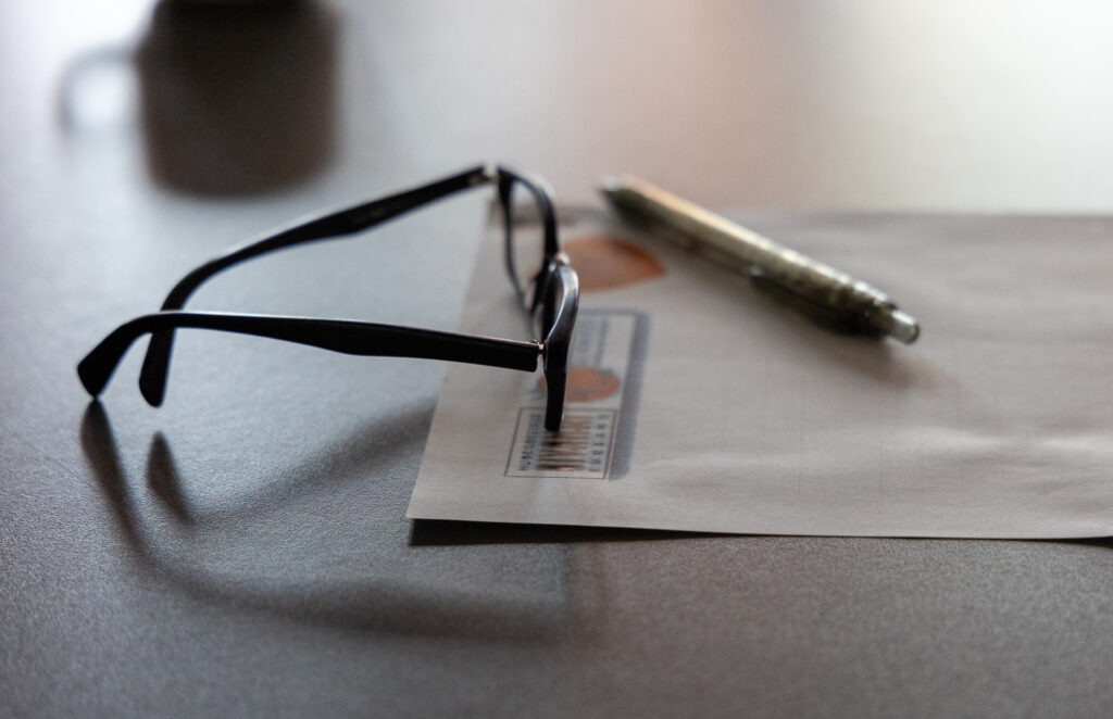 silmälasit ja kynä pöydllä